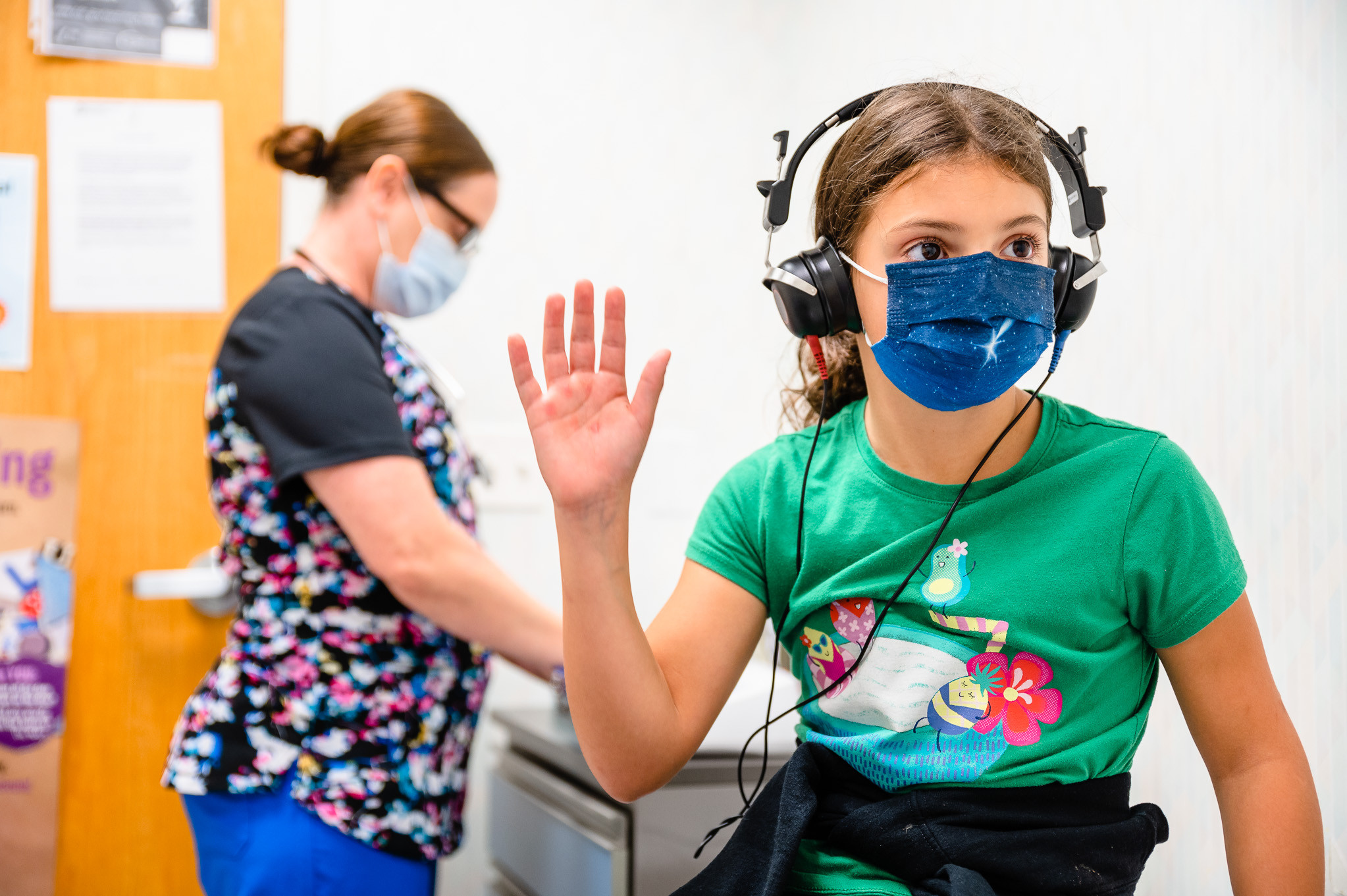 a girl raising a hand during a hearing test