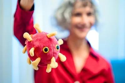 a woman holding a toy covid stuffed animal